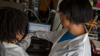 Two students pointing at data on a computer screen