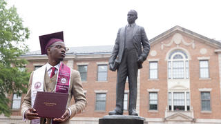 Alumnus Derrick Stanfield standing in front of Shepard statue