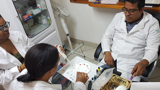 Students using pipette while a professor supervises 