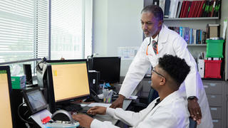 Two researchers discussing data on a computer screen