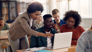 three students looking at a laptop