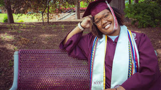 Graduate Netanya Dennis sitting on bench