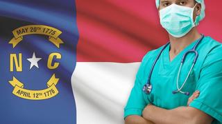 Male nurse standing in front of an NC flag