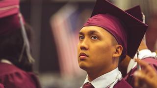 Gradutating student sitting in cap and gown