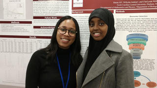 students smiling in front of their presentation boards