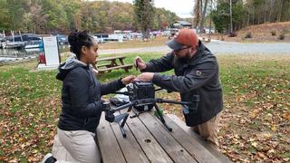 2 students working on drone on picnic table