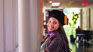 Law school graduate Maeva Hassani smiles while wearing her regalia