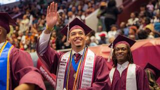spring 2025 commencement photo male student waving to the crowd