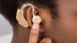 Woman holding hearing aid to ear