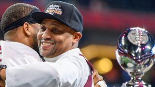 NCCU football coach celebrates championship victory beside trophy at Celebration Bowl.