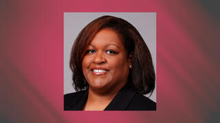 Professional headshot of Charmaine Fuller Cooper smiling in a black blazer against a neutral studio background.