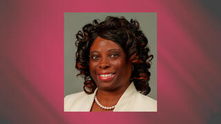 Professional portrait of Dr. Deanna Townsend wearing a cream blazer and pearl necklace with curled highlighted hair.