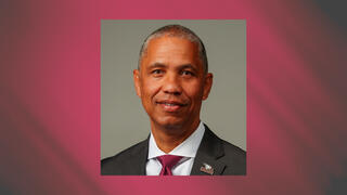 Executive portrait of Eddie Buffaloe Jr. in a gray suit and red tie with NCCU lapel pin.