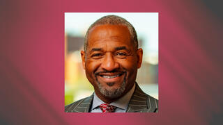 Professional business headshot of Gregory Scott smiling in a pinstripe suit and patterned red tie.
