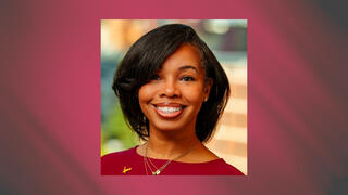 Professional portrait of Renee Clark smiling in a burgundy dress with layered necklaces and styled black hair.