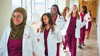 nursing students walking down a hallway, smiling