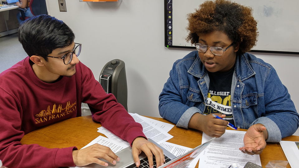 Two students sitting at a table talking.