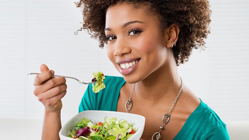 Woman with a salad smiling towards viewer.
