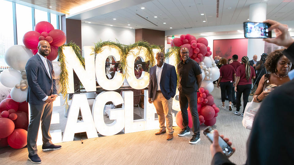 A group of people posing in front of NCCU Eagles sign