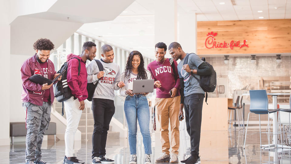 Student in Front of Chick-fil-A, looking at a laptop