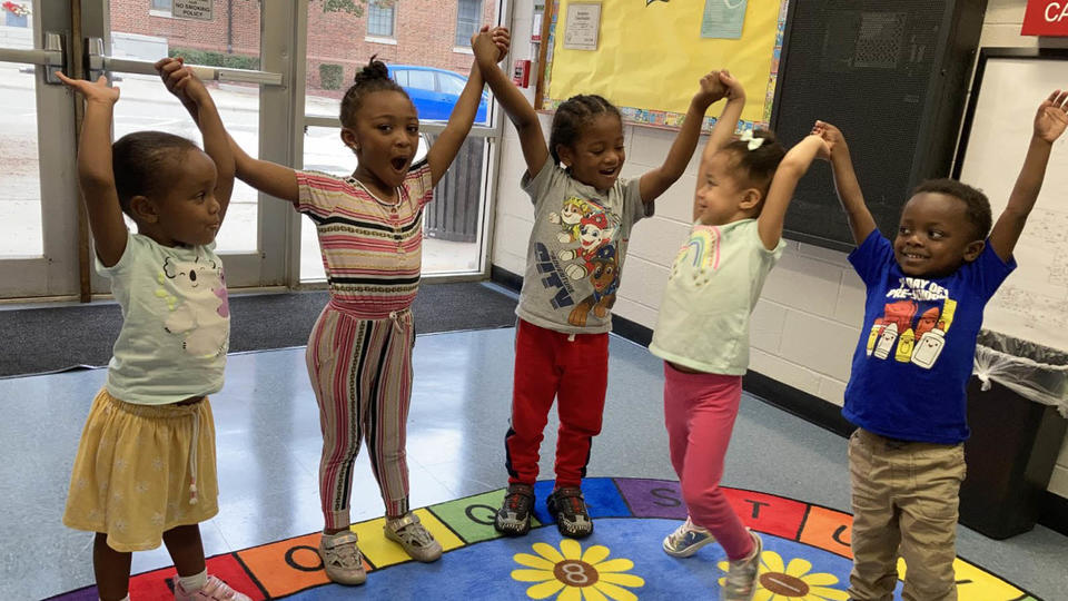 children with their hands up, holding hands