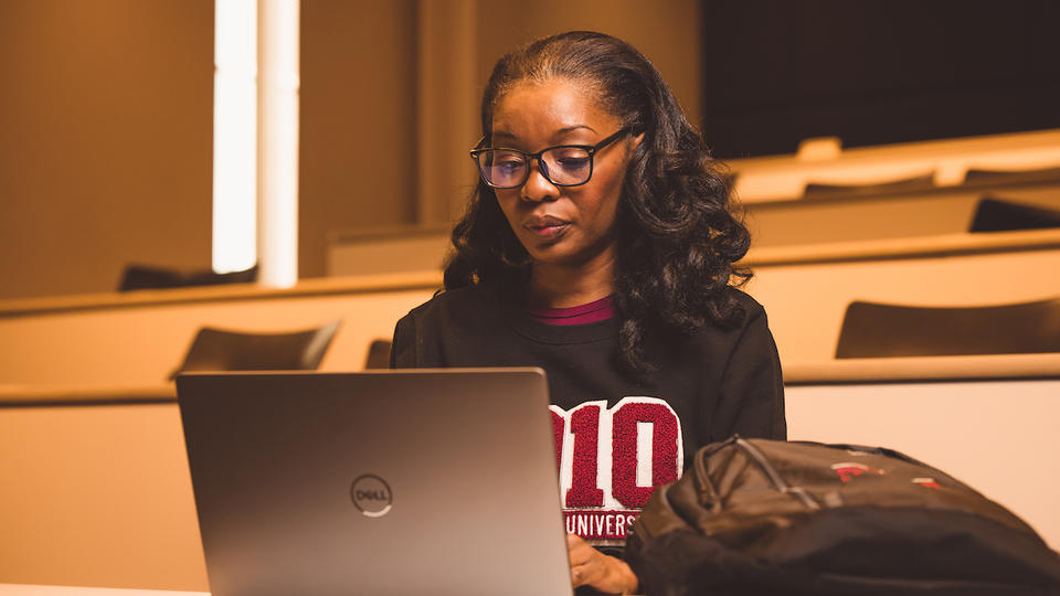 Student sitting in a lecture hall looking at her computer