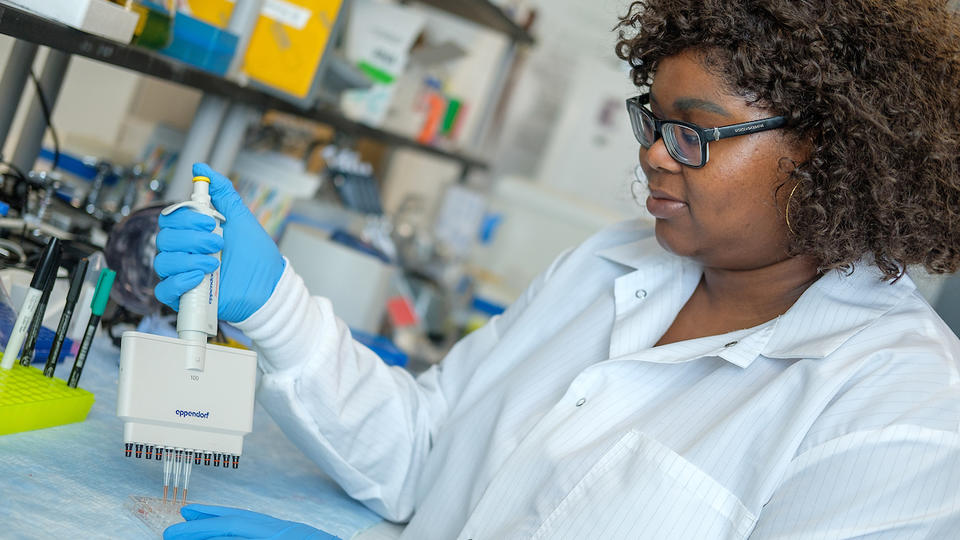 A young black woman with glasses using a multichannel pippete to collect samples