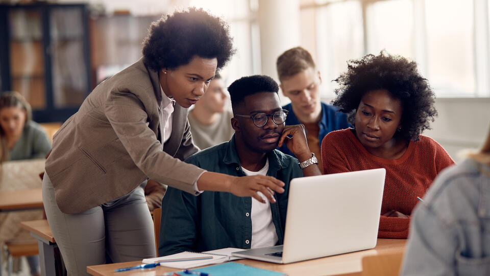 three students looking at a laptop