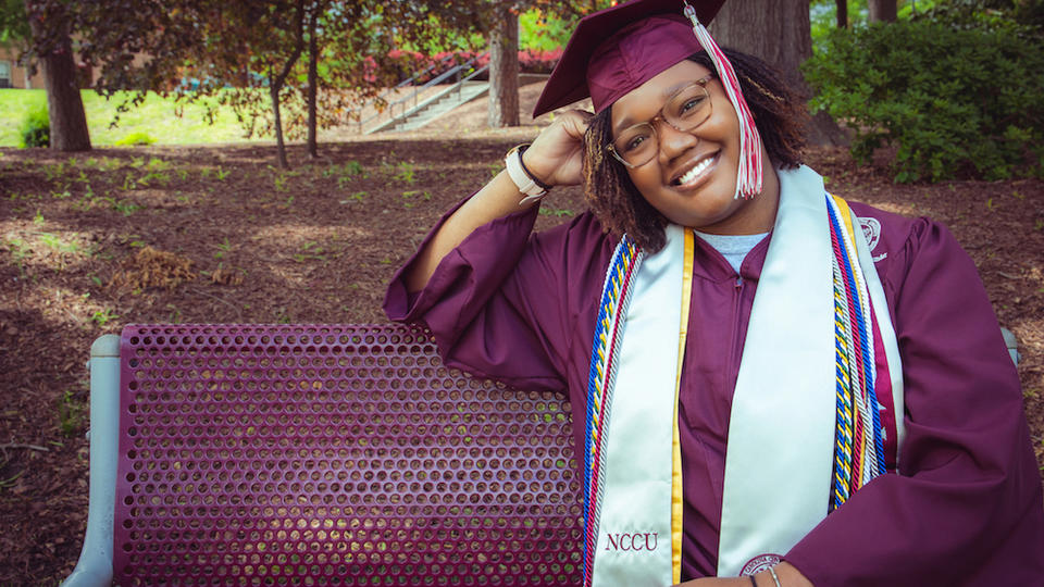 Graduate Netanya Dennis sitting on bench