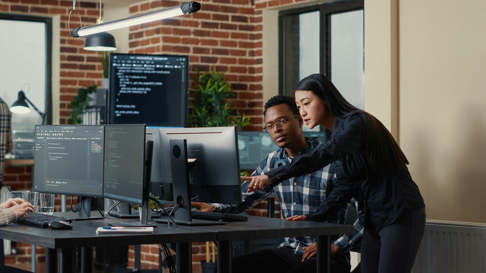 Black male and Asian female working in front of a computer
