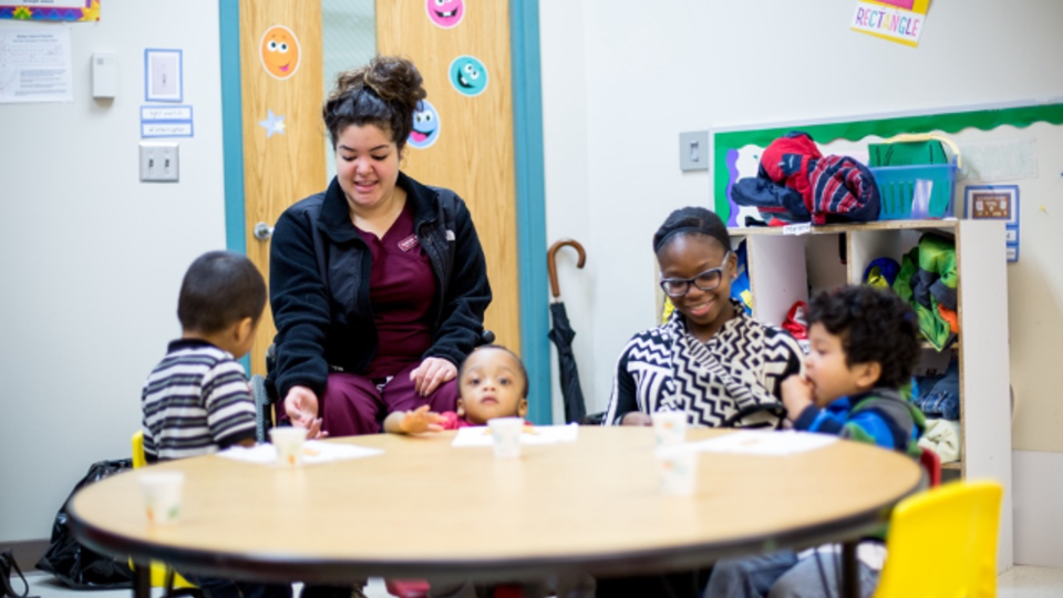 An adult working with a group of children around a small table