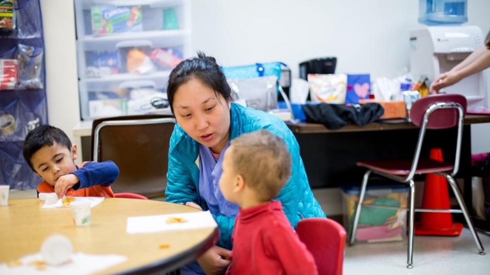 An adult working closely with a child at a small table