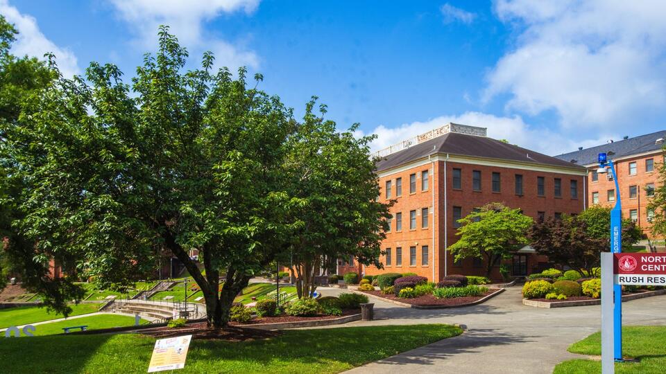 View of North Carolina Central University's campus with brick buildings, trees, lawns, and walkways on a sunny day.