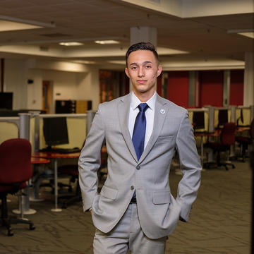 Computers surround male student in suit.