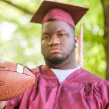 Graduate holding football.
