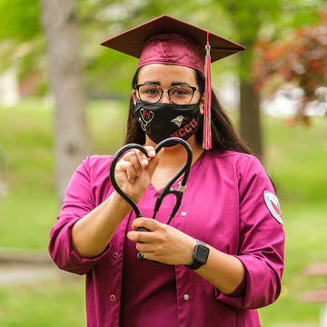 Nursing graduate holding medical equipment.