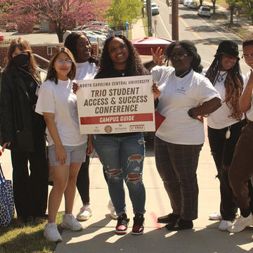 Students holding sign that says "TRIO Student Access & Success Conferences, Campus Guide"
