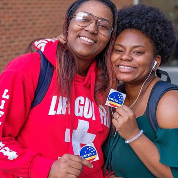 A couple of NCCU students smiling and posing for the camera with their "I Voted" stickers