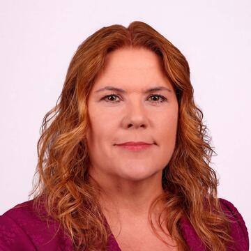 Professional headshot of Lauri Wilcox wearing a burgundy blazer, smiling against a neutral background.