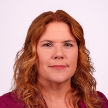 Professional headshot of Lauri Wilcox wearing a burgundy blazer, smiling against a neutral background.
