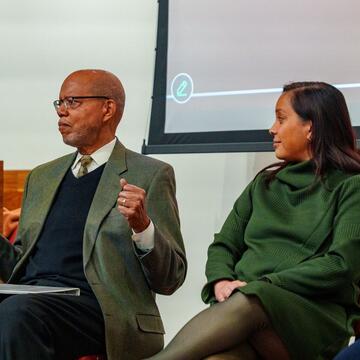 Three panelists seated on stage during a discussion at the Building Black North Carolina forum