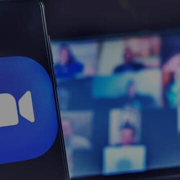 Person holding a phone with the Zoom logo, while in a Zoom meeting