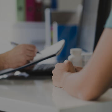 A stock image of a healthcare professional taking notes during a doctor appointment