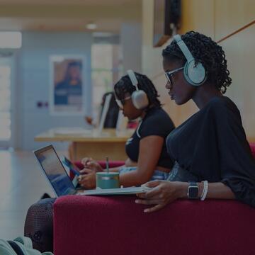 Students wearing headphones while concentrating on laptops