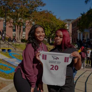 Image of two women holding an NCCU jersey