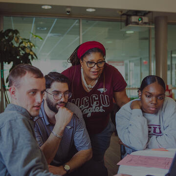 A group of five people looking at a laptop