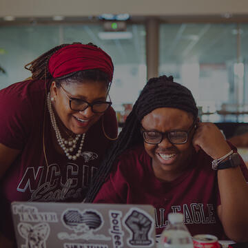 Two people looking at a laptop and smiling