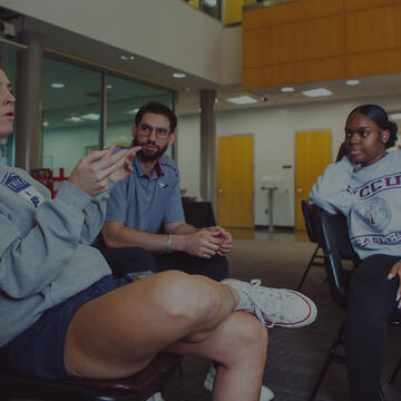 Three people sitting in chairs and having a discussion