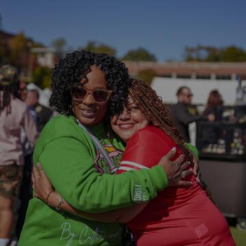 Two women hug at an outdoor event