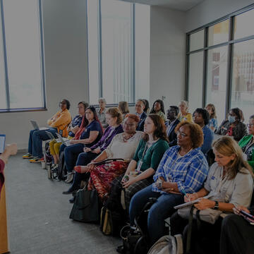 People sitting in a large group and listening to a speaker